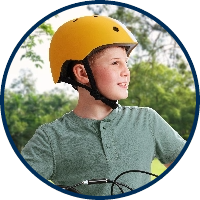 Right-facing profile of young boy with yellow helmet against park background